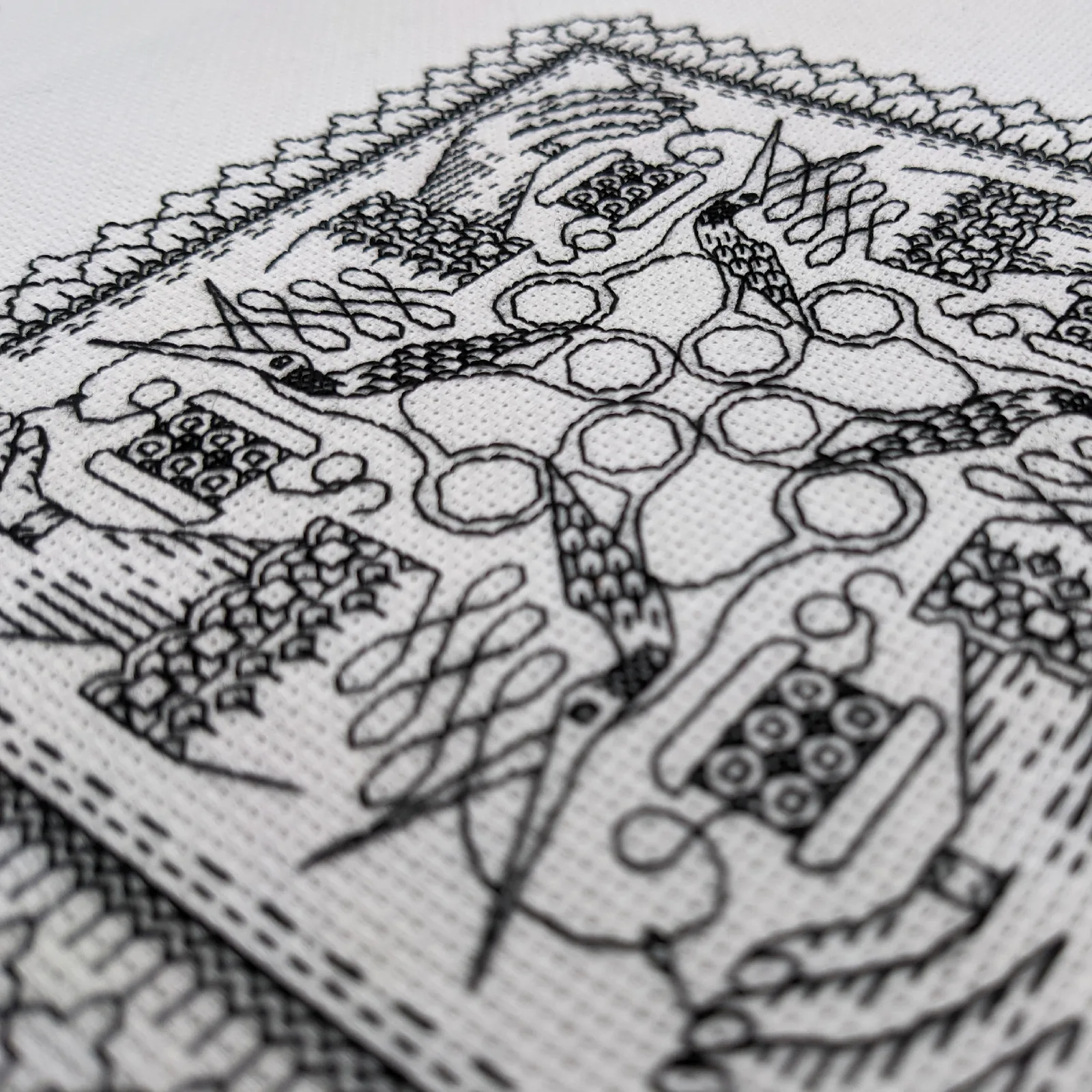 Détail d'une broderie blackwork avec motifs géométriques en fil noir sur toile claire
