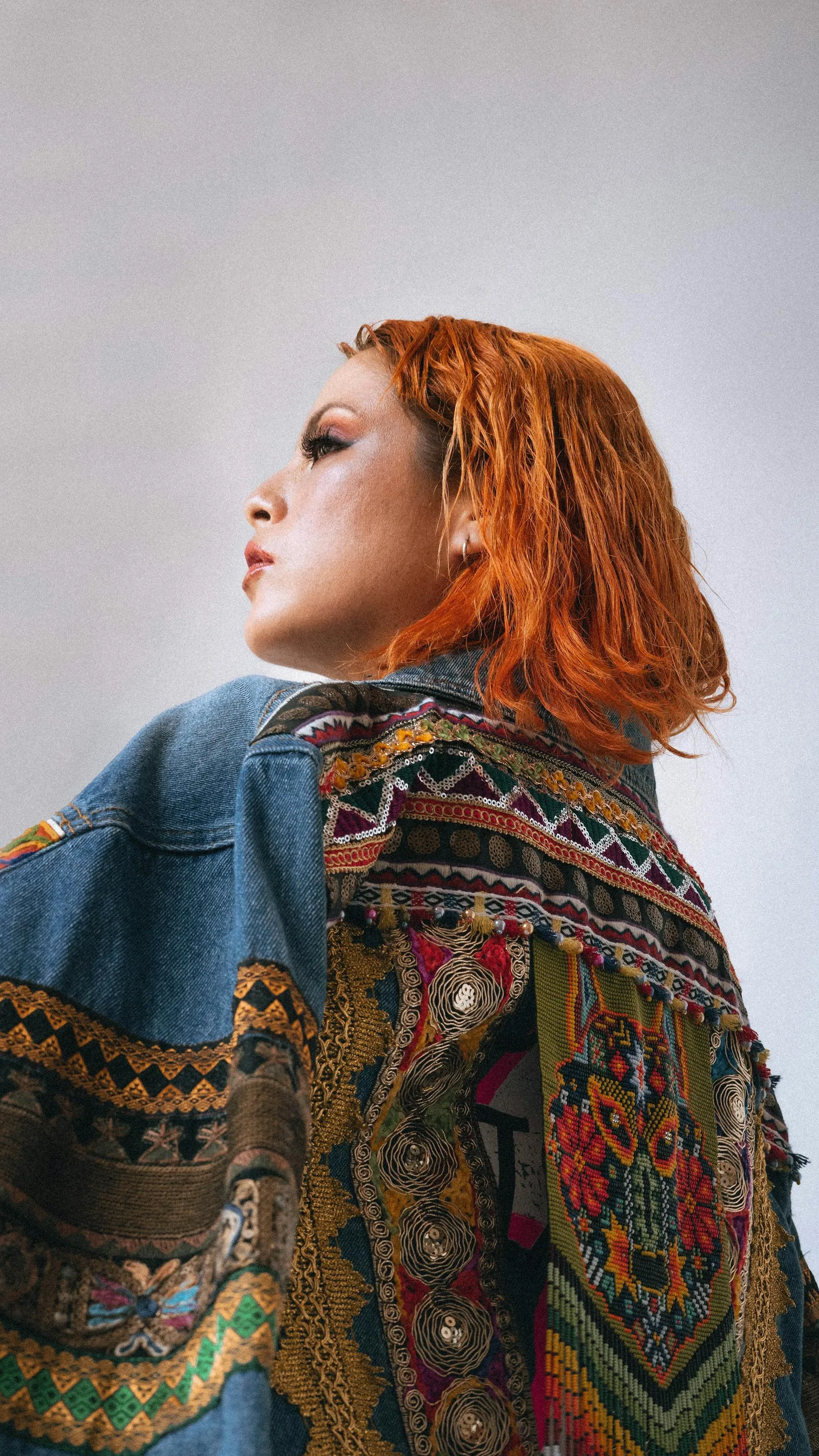 Veste en jean brodée avec motifs ethniques colorés portée par une jeune femme