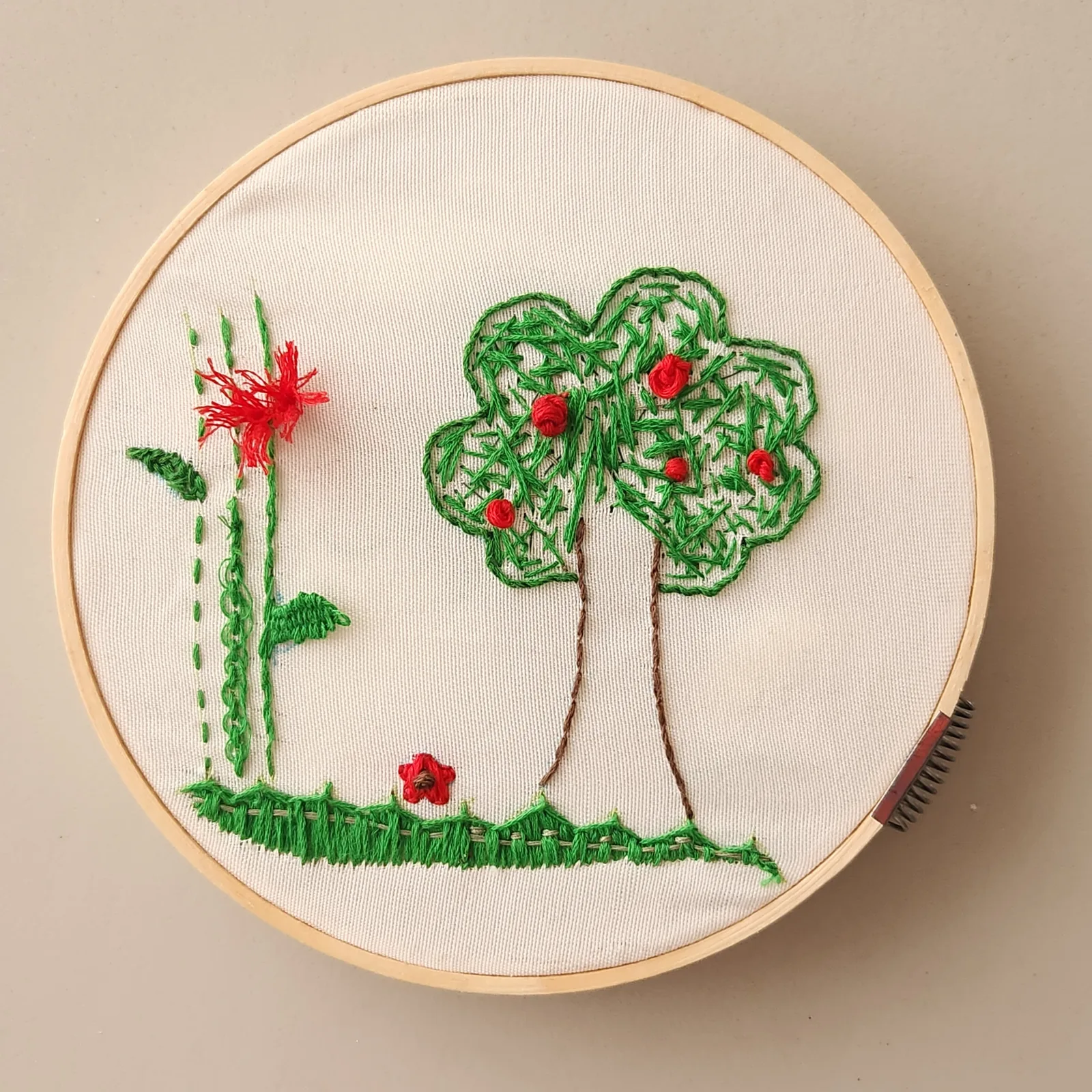 Broderie champêtre avec arbre et fleurs rouges dans un cerceau en bois — résultat en broderie à l'aiguille