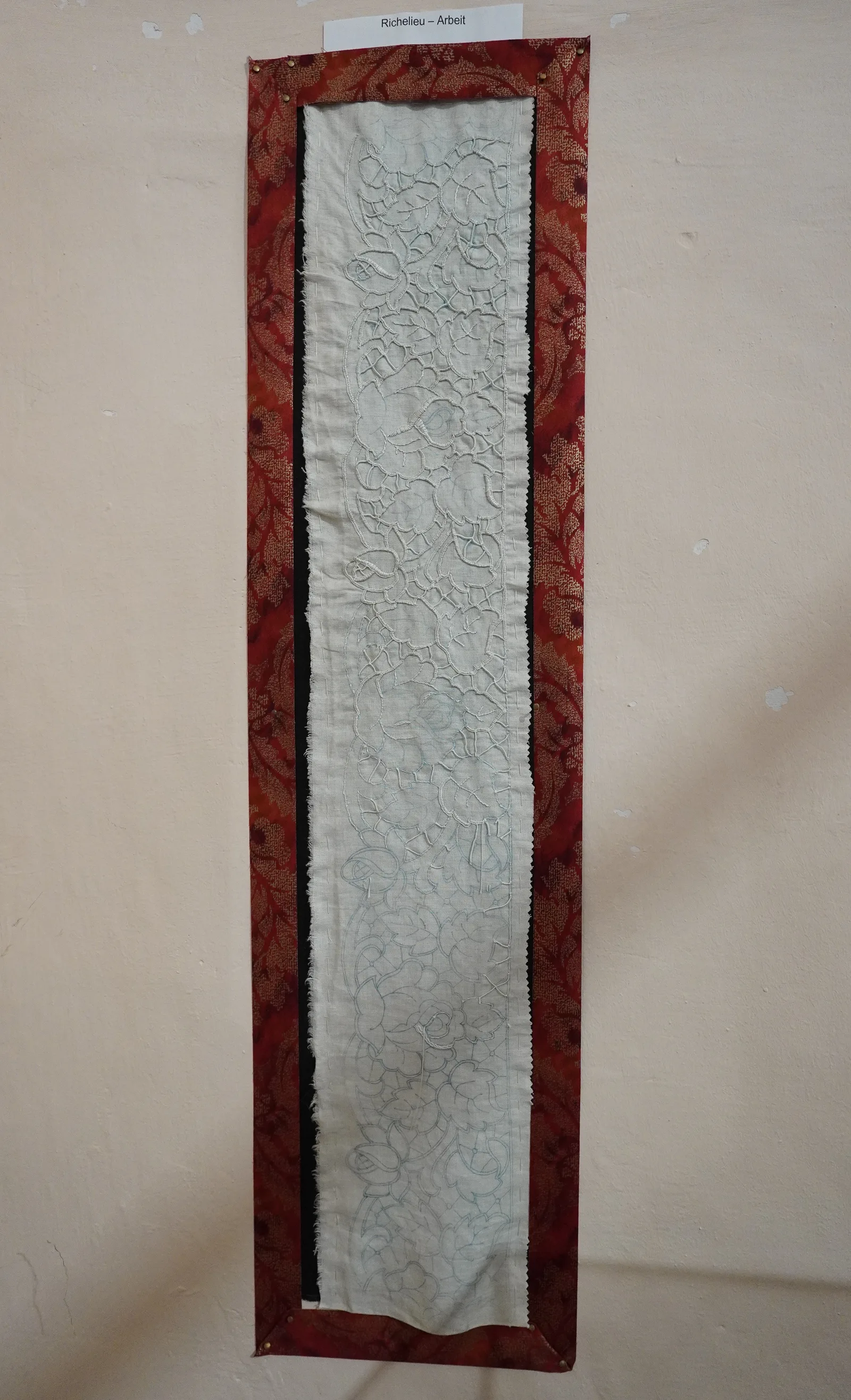 Panneau de broderie Richelieu encadré en musée — panel de lin avec travail ajouré floral et bordure en velours rouge