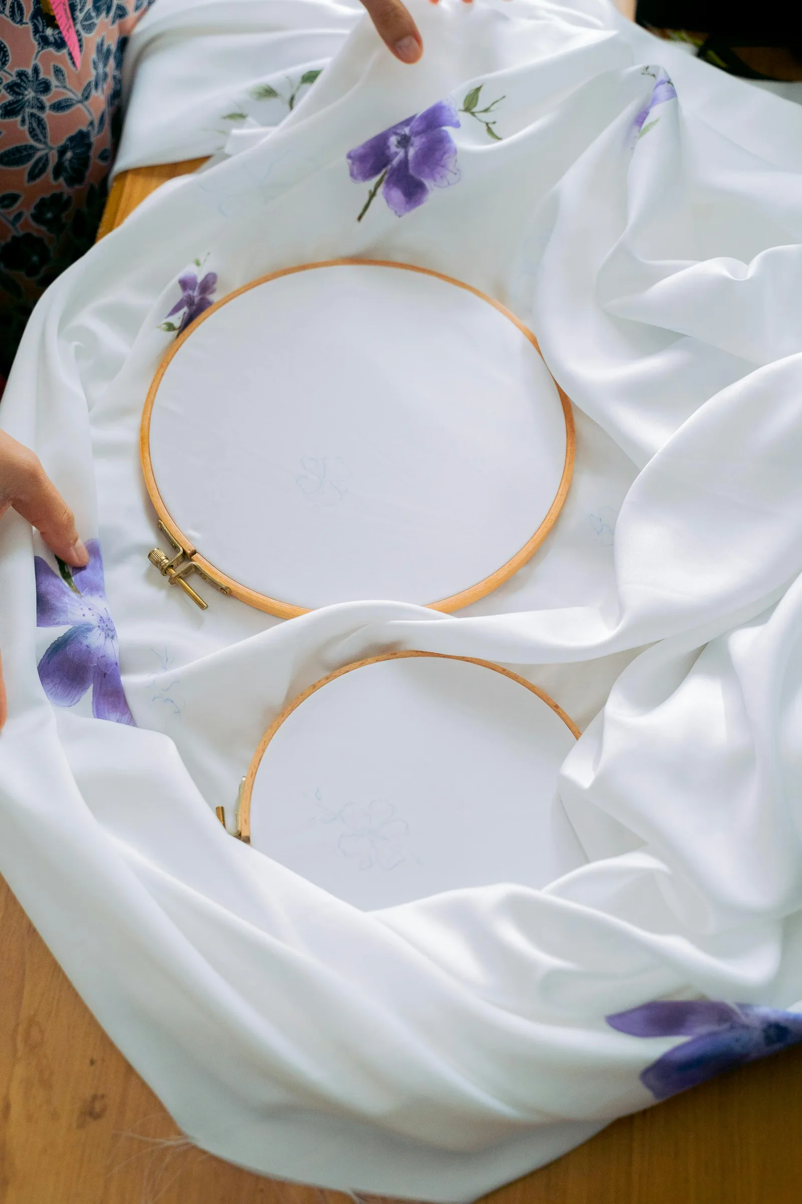 Cerceaux de broderie vides sur tissu blanc imprimé de fleurs violettes, préparation pour décoration murale chambre enfant