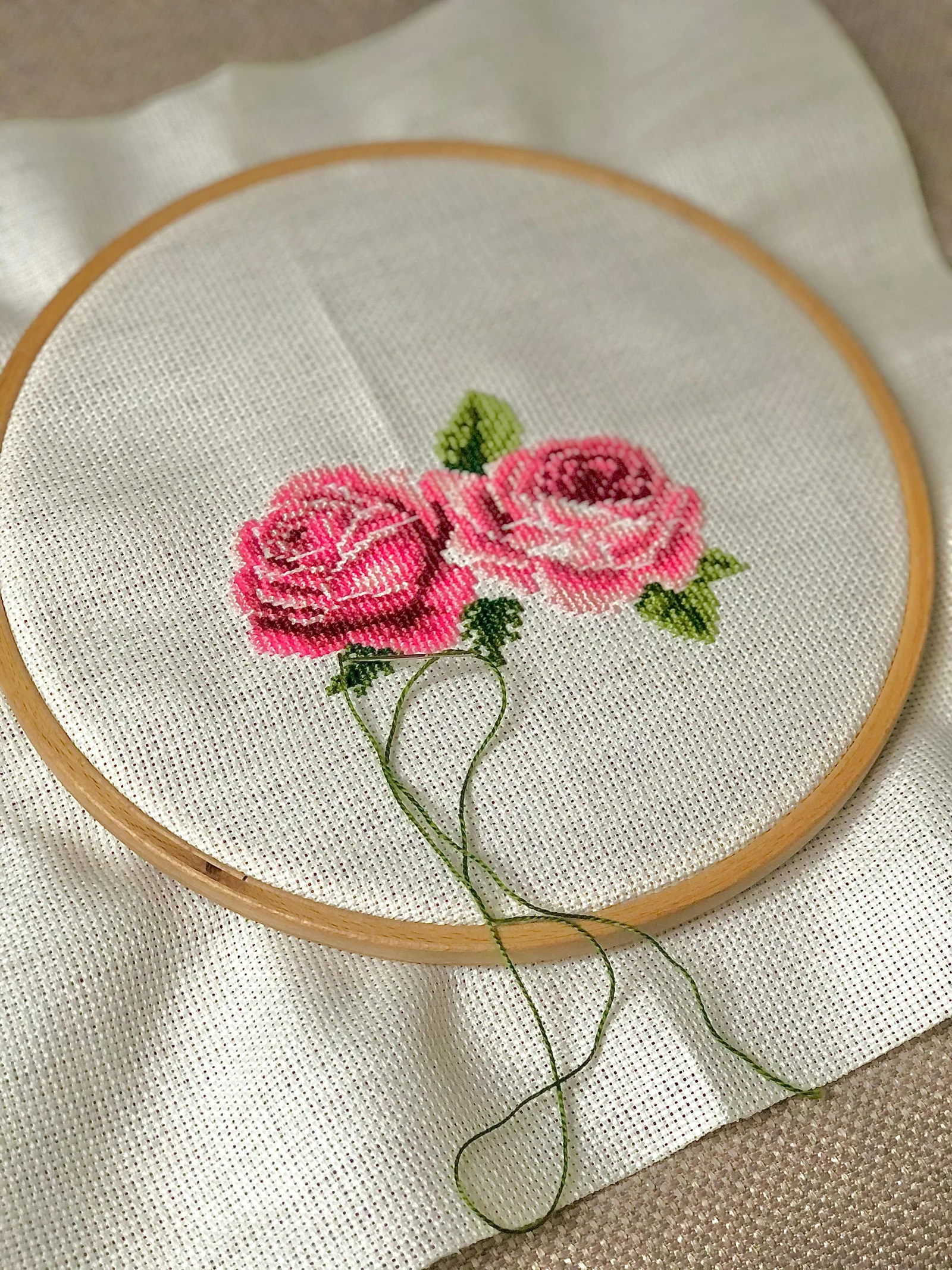 Point de croix roses dans un cerceau sur tissu Aïda blanc — technique de broderie sur toile comptée