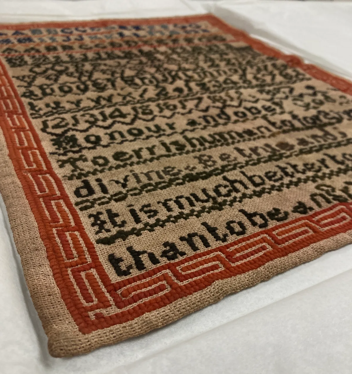 Ancien sampler brodé posé à plat pour nettoyage et conservation textile