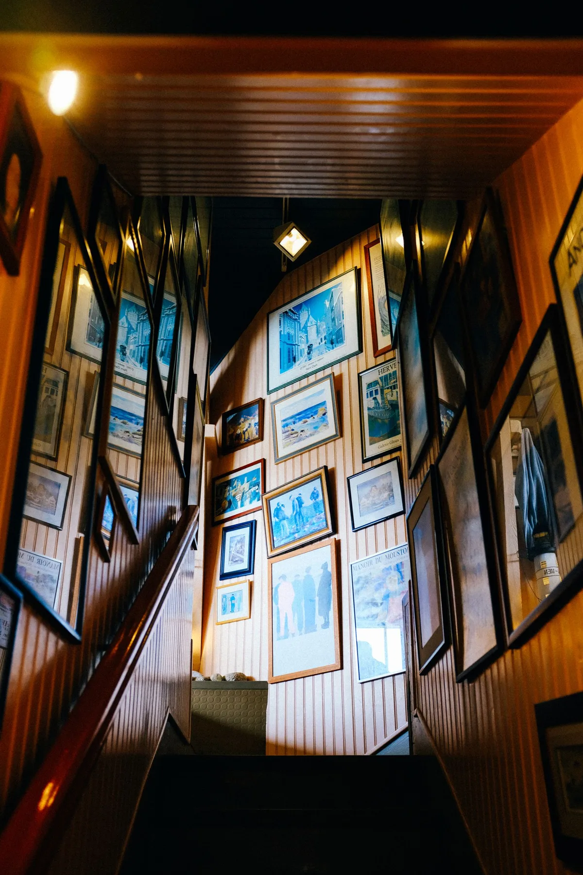 Galerie de cadres encadrés disposés le long d'un escalier, composition murale avec de nombreux tableaux