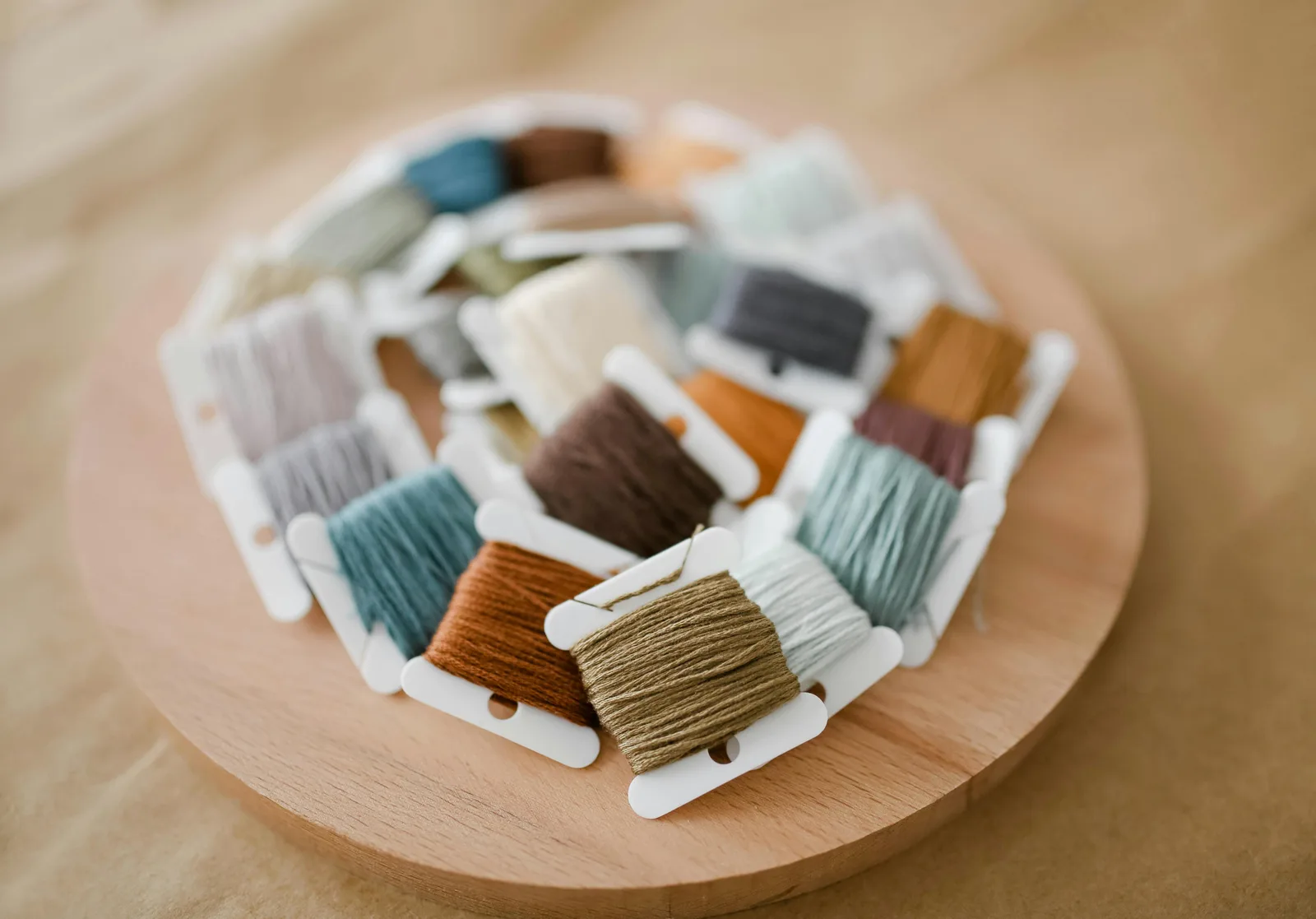 Bobines de fils de broderie en tons neutres sur un plateau en bois — palette idéale pour tester les correspondances DMC Anchor