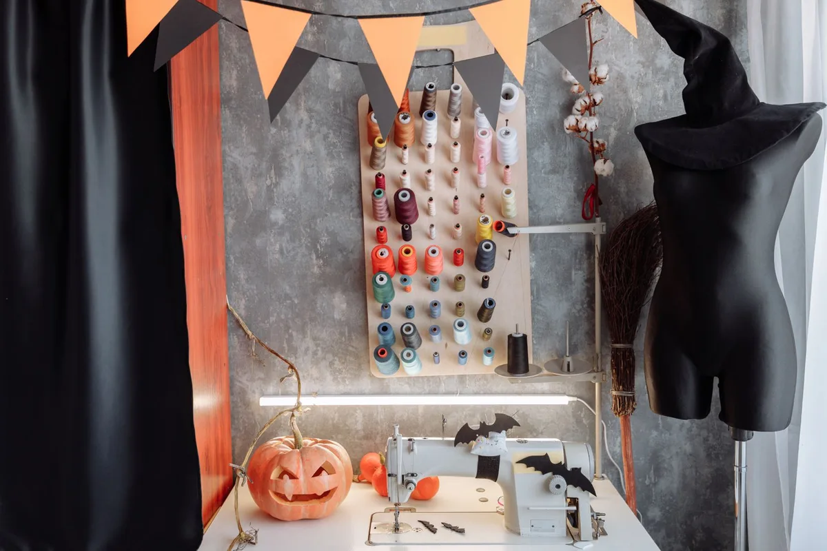 Atelier de couture décoré pour Halloween avec citrouille sculptée, fils colorés et chapeau de sorcière