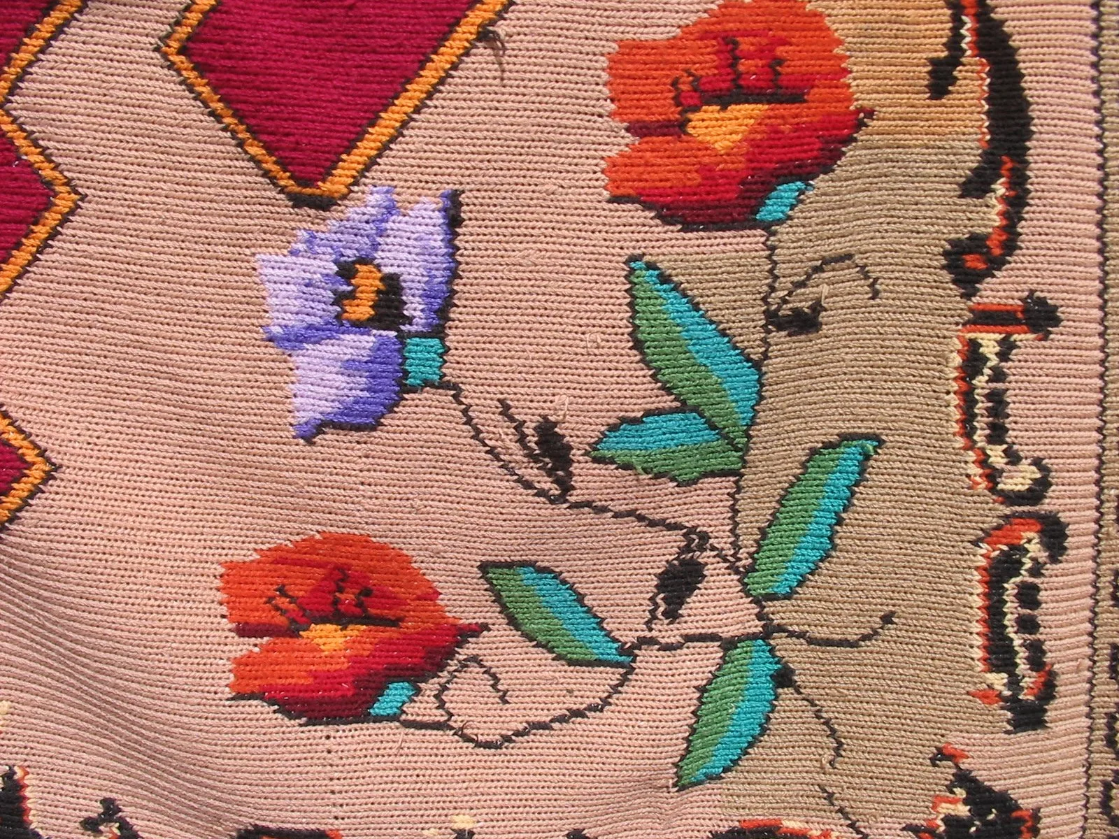 Détail d'une nappe brodée traditionnelle roumaine — motifs floraux en rouge et violet sur fond clair