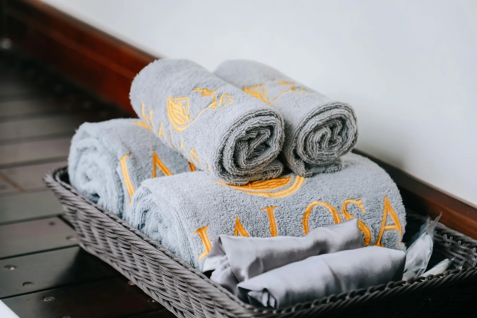 Serviettes de bain grises brodées d'un motif doré dans un panier osier — linge de bain personnalisé