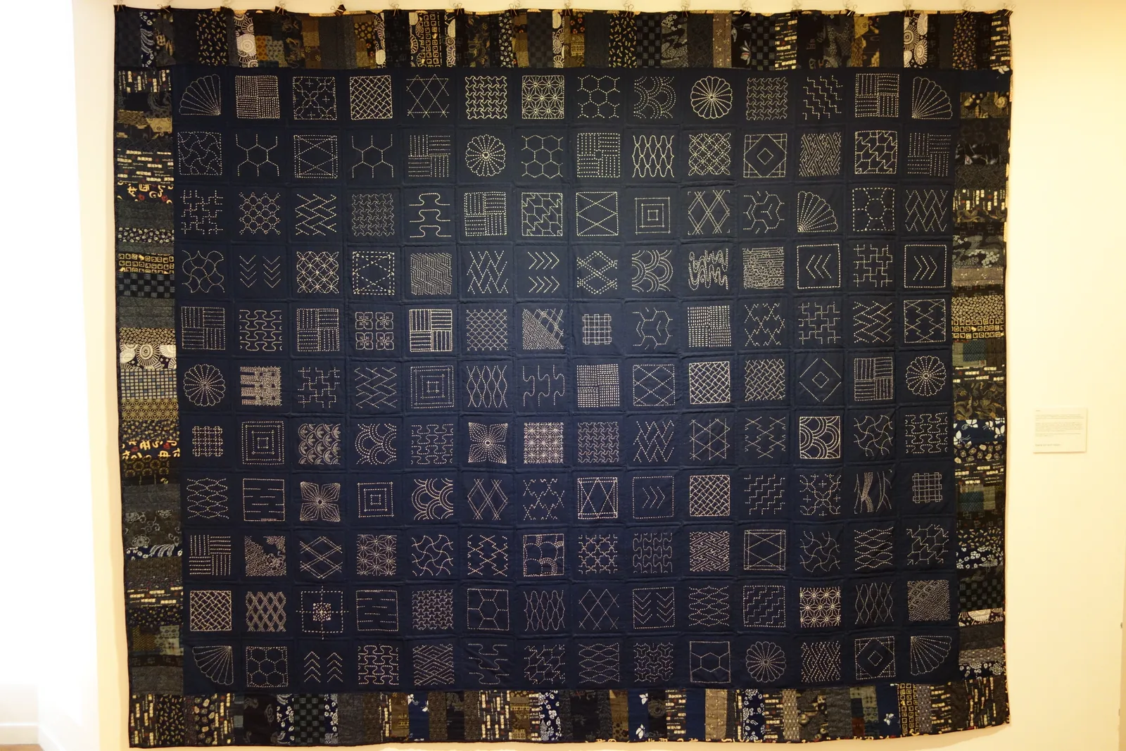 grand sampler sashiko avec multiples motifs géométriques sur tissu indigo