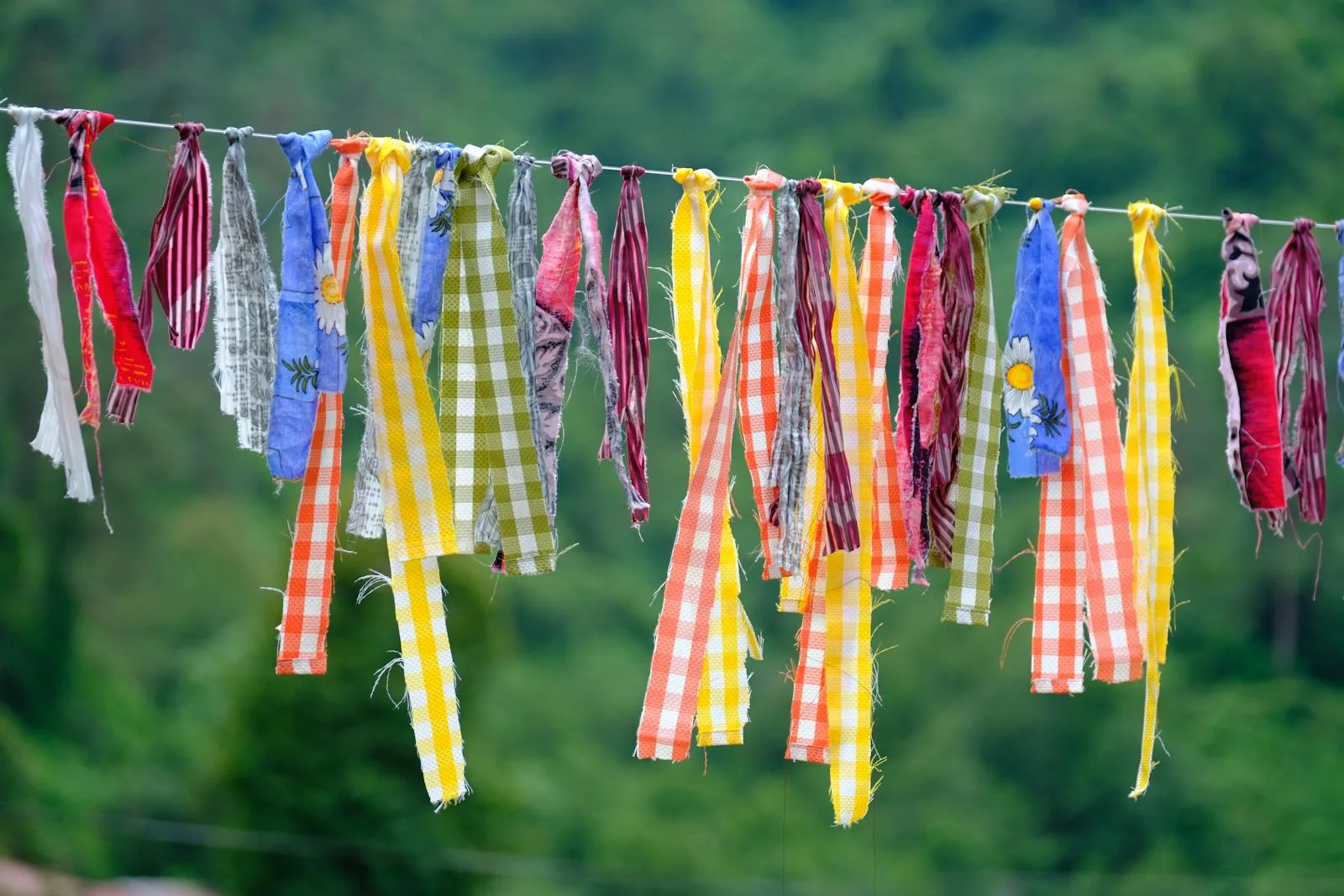 guirlande de banderoles textiles colorées suspendues en extérieur dans un jardin verdoyant