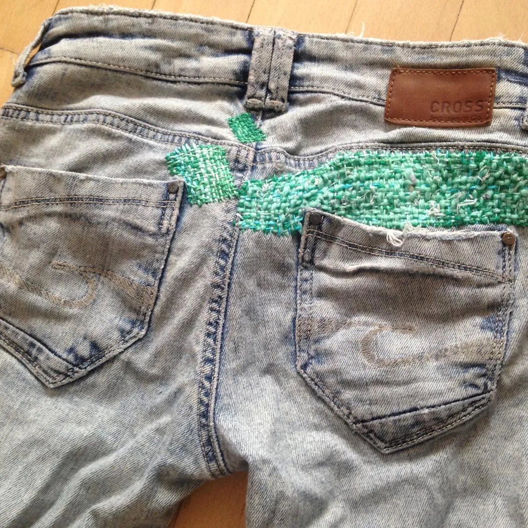 Jean upcyclé avec reprise visible en fil vert sur la poche arrière, technique de visible mending